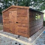 Pressure-treated wooden pent shed with single door and side window, suitable for compact garden storage.