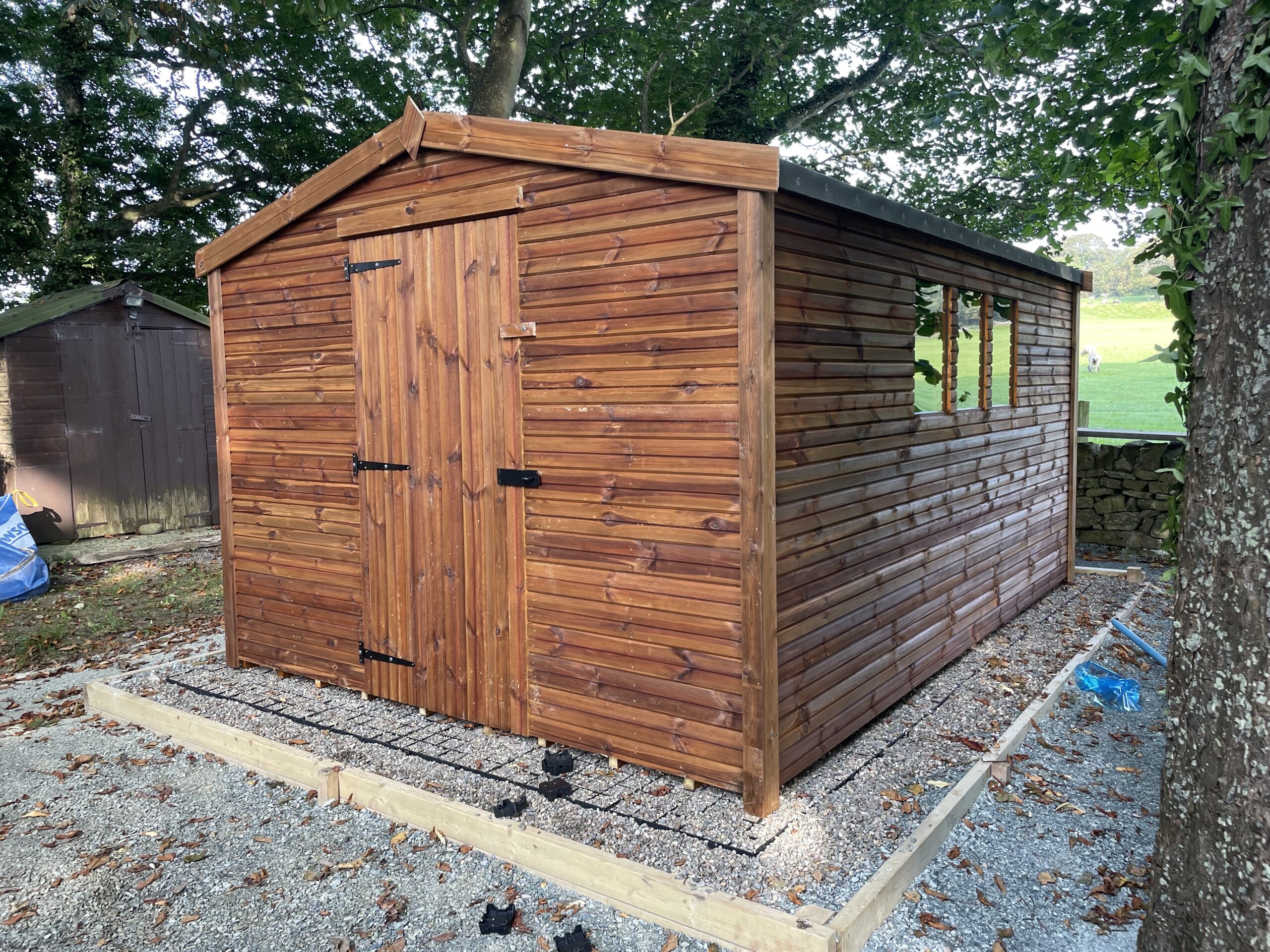 Pressure-treated wooden pent shed with single door and side window, suitable for compact garden storage.
