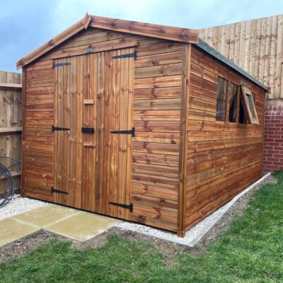 Wooden garden shed with double doors and apex roof, installed on a concrete base in a residential garden.