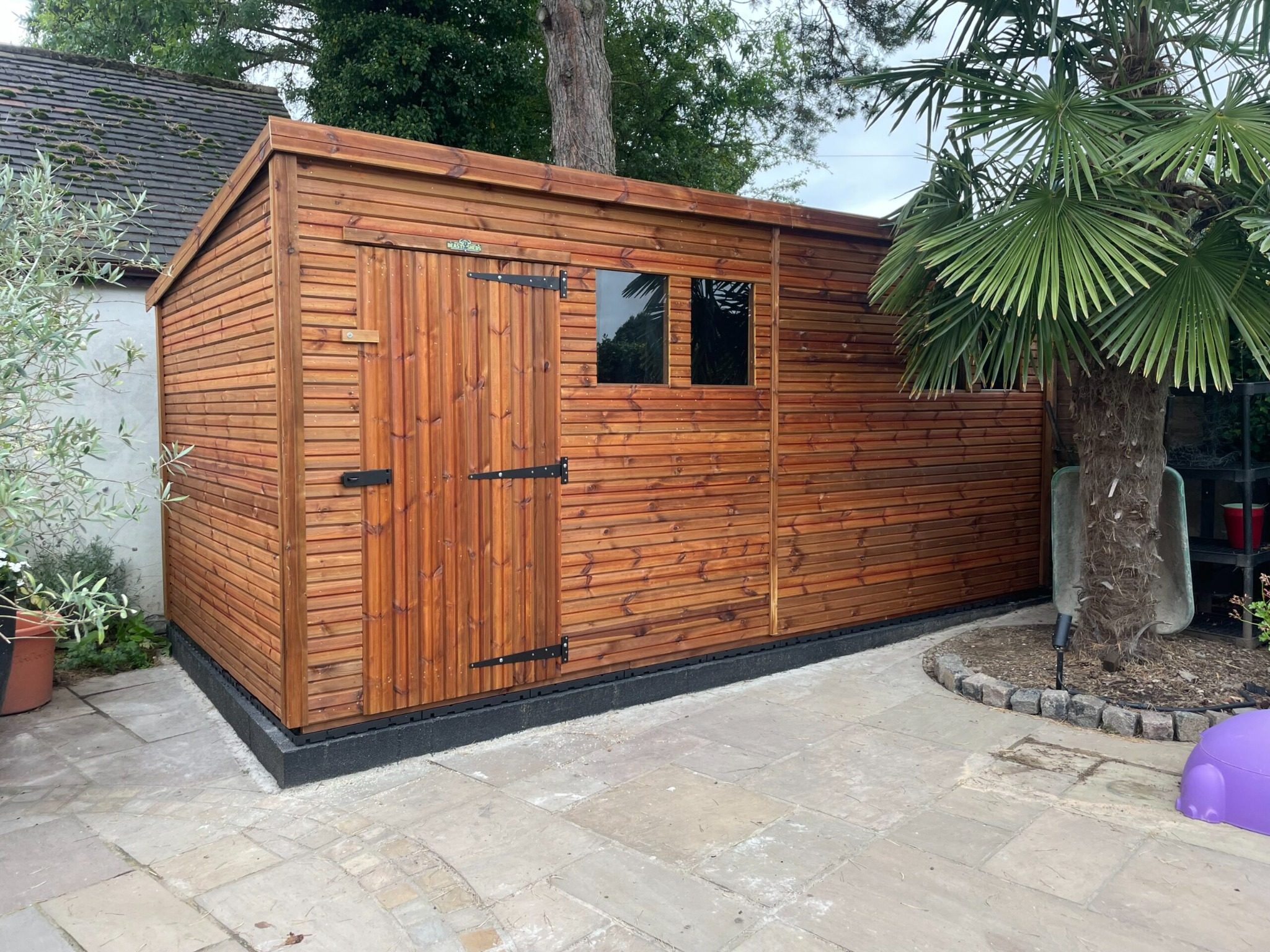 Side angle of a heavy duty pent garden shed with a single door and two windows