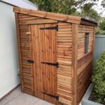 Small tantalised garden shed with onduline roofing and a single door